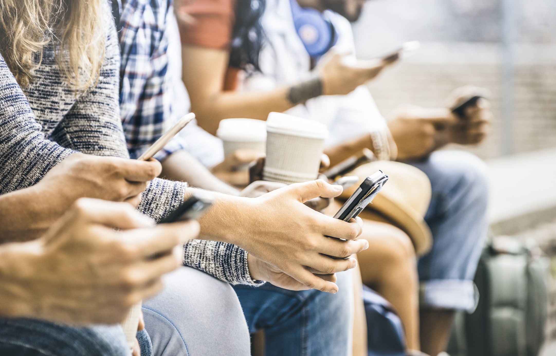 Multicultural friends group using smartphones with coffee