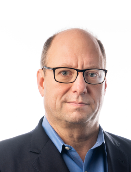 Randy wearing glasses and a blue shirt with a serious expression