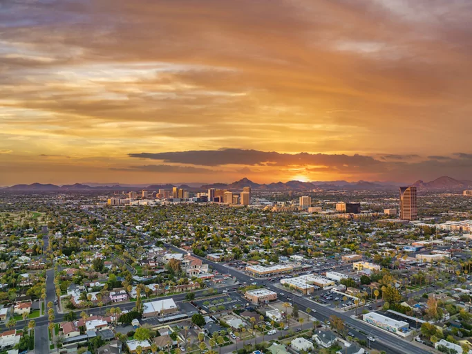 Aerial view of cityscape at sunset with mountains.