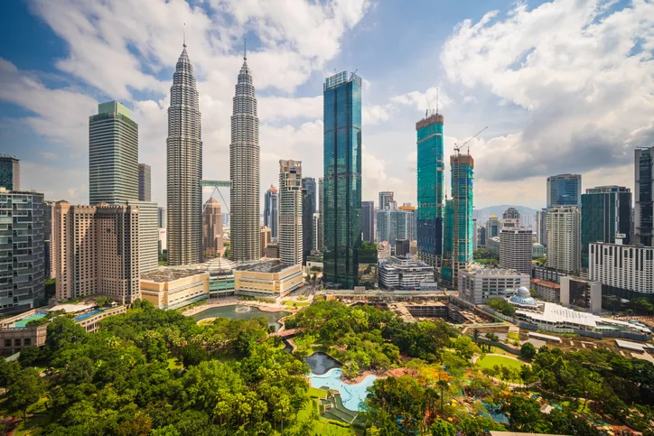 Kuala Lumpur skyline with Petronas Towers and lush park.