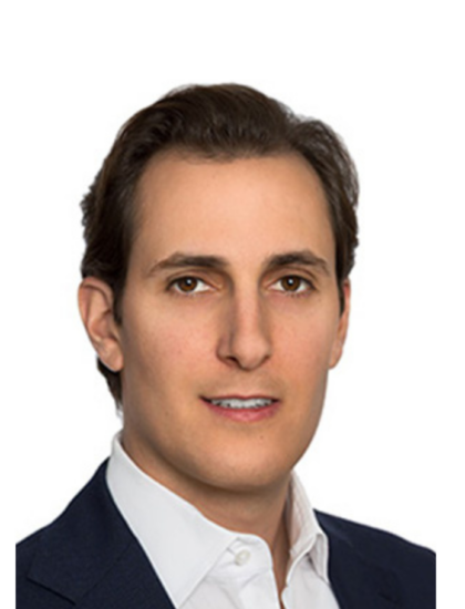 A person in a dark suit and white shirt against a plain white background